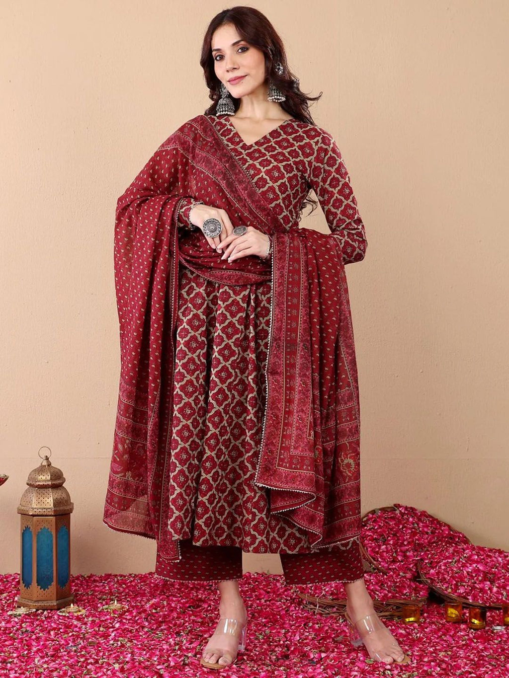 Woman in a maroon patterned outfit with a matching dupatta on a beige background