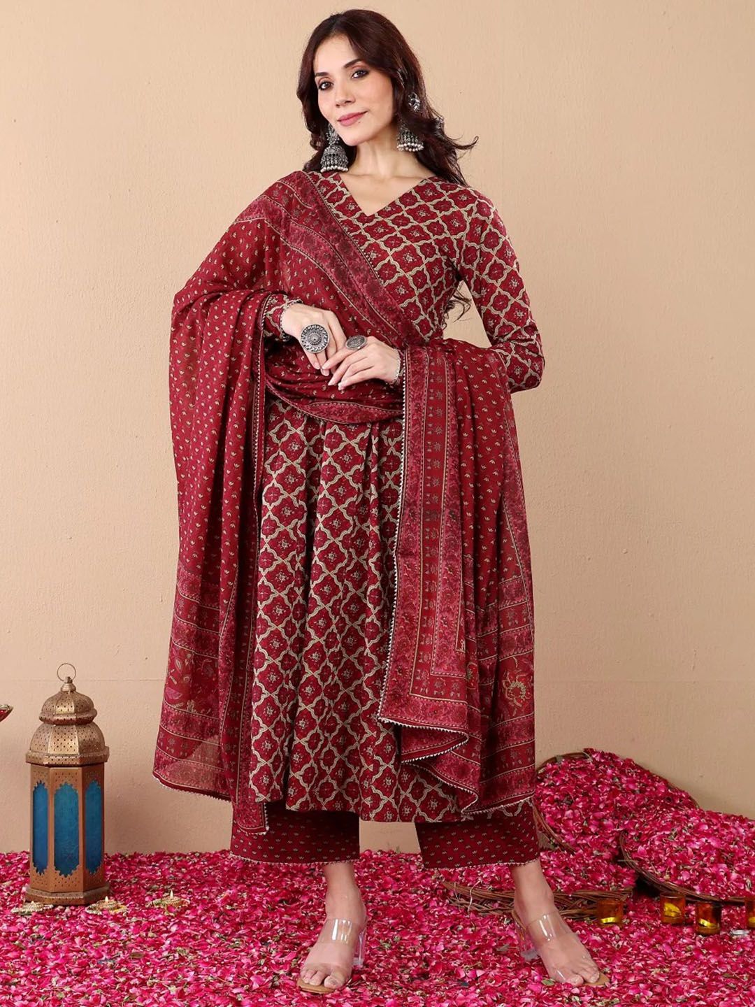 Woman in a maroon patterned outfit with a matching dupatta on a beige background