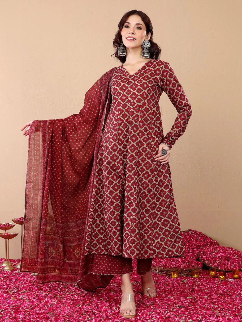 Woman wearing a red patterned outfit with a matching dupatta on a beige background
