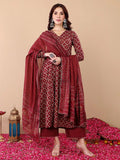 Woman wearing a red patterned traditional outfit with a dupatta on a beige background
