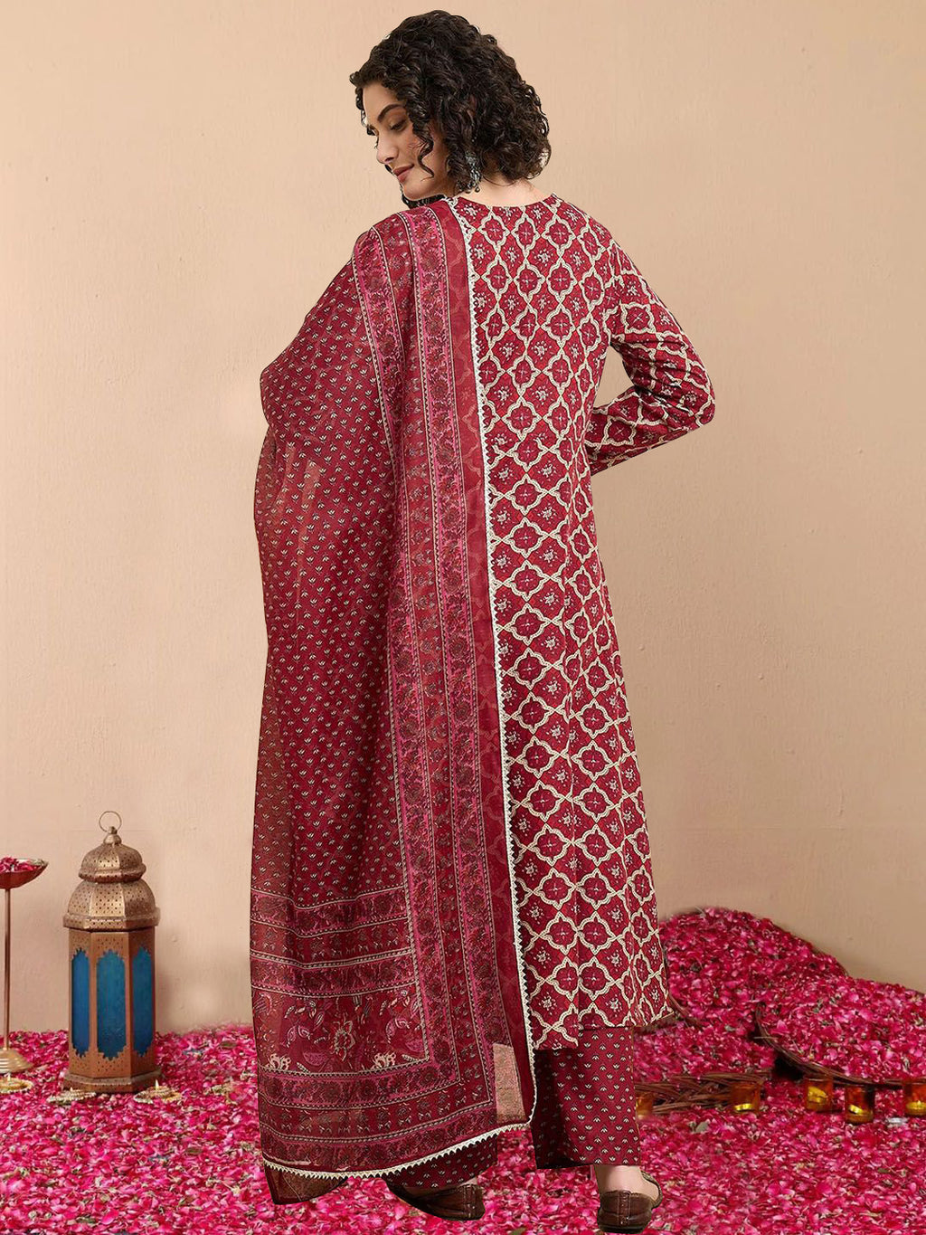 Woman wearing a red and white patterned dress on a pink floral carpet with decorative items.