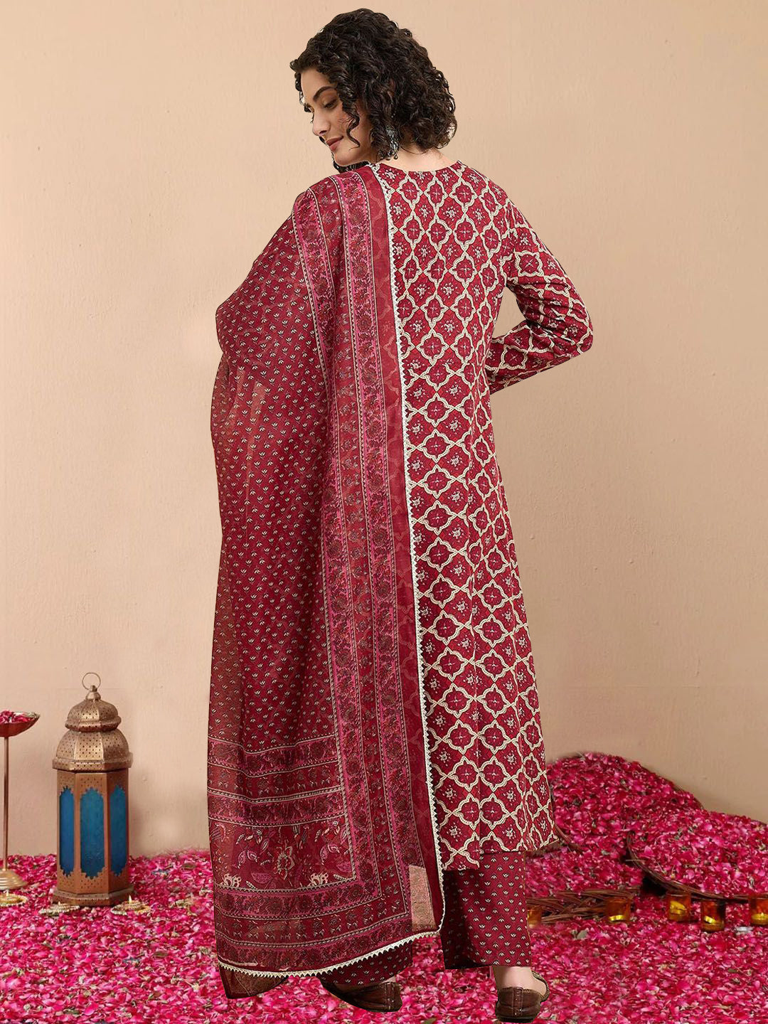 Woman wearing a red and white patterned dress on a pink floral carpet with decorative items.