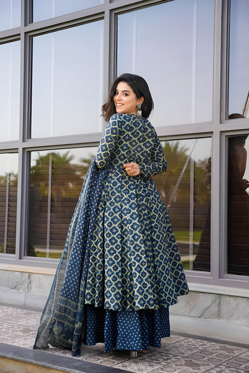 Woman in a blue patterned traditional outfit standing in front of a glass building.