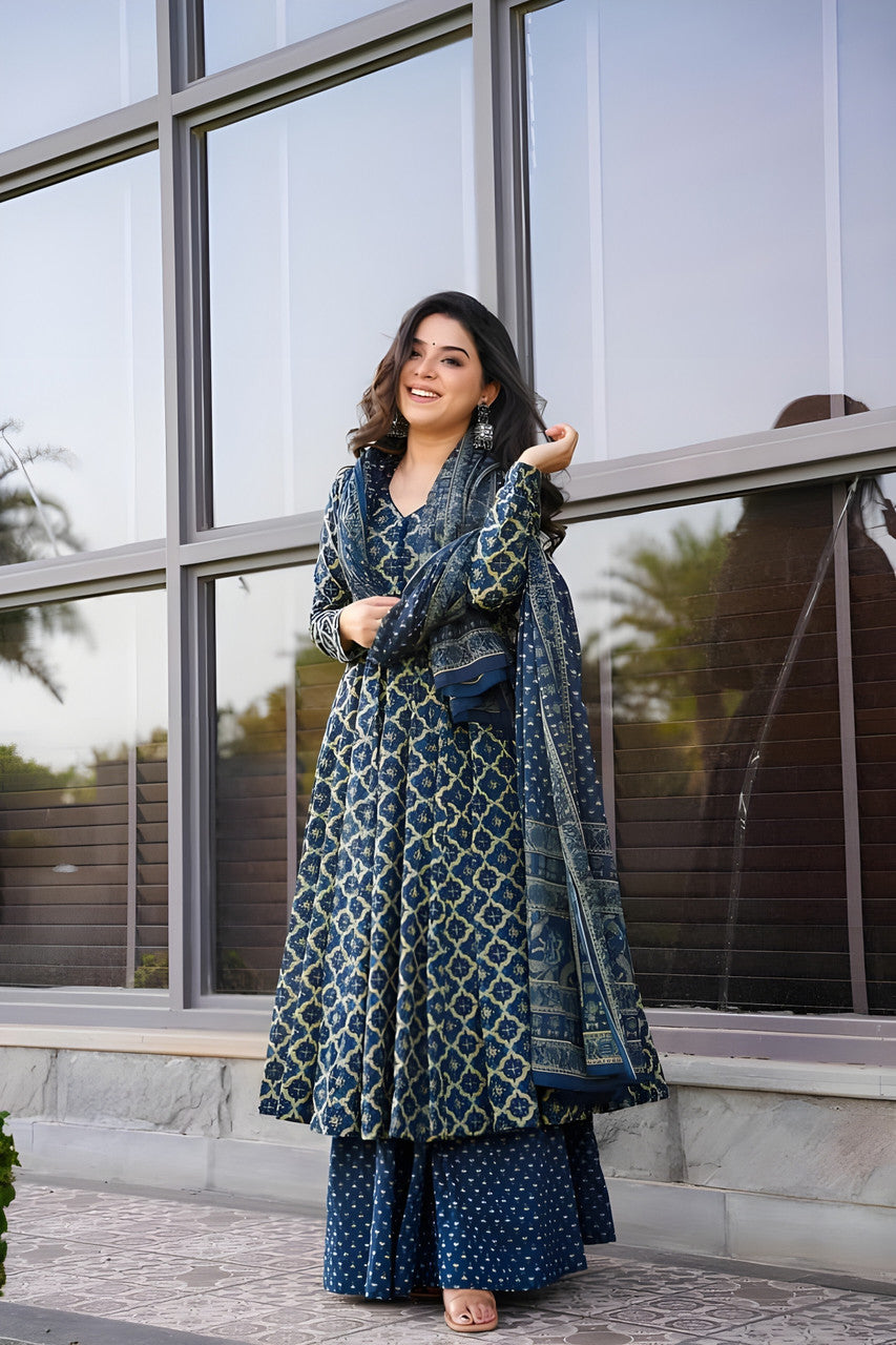 Woman in a blue patterned outfit standing in front of a glass building.