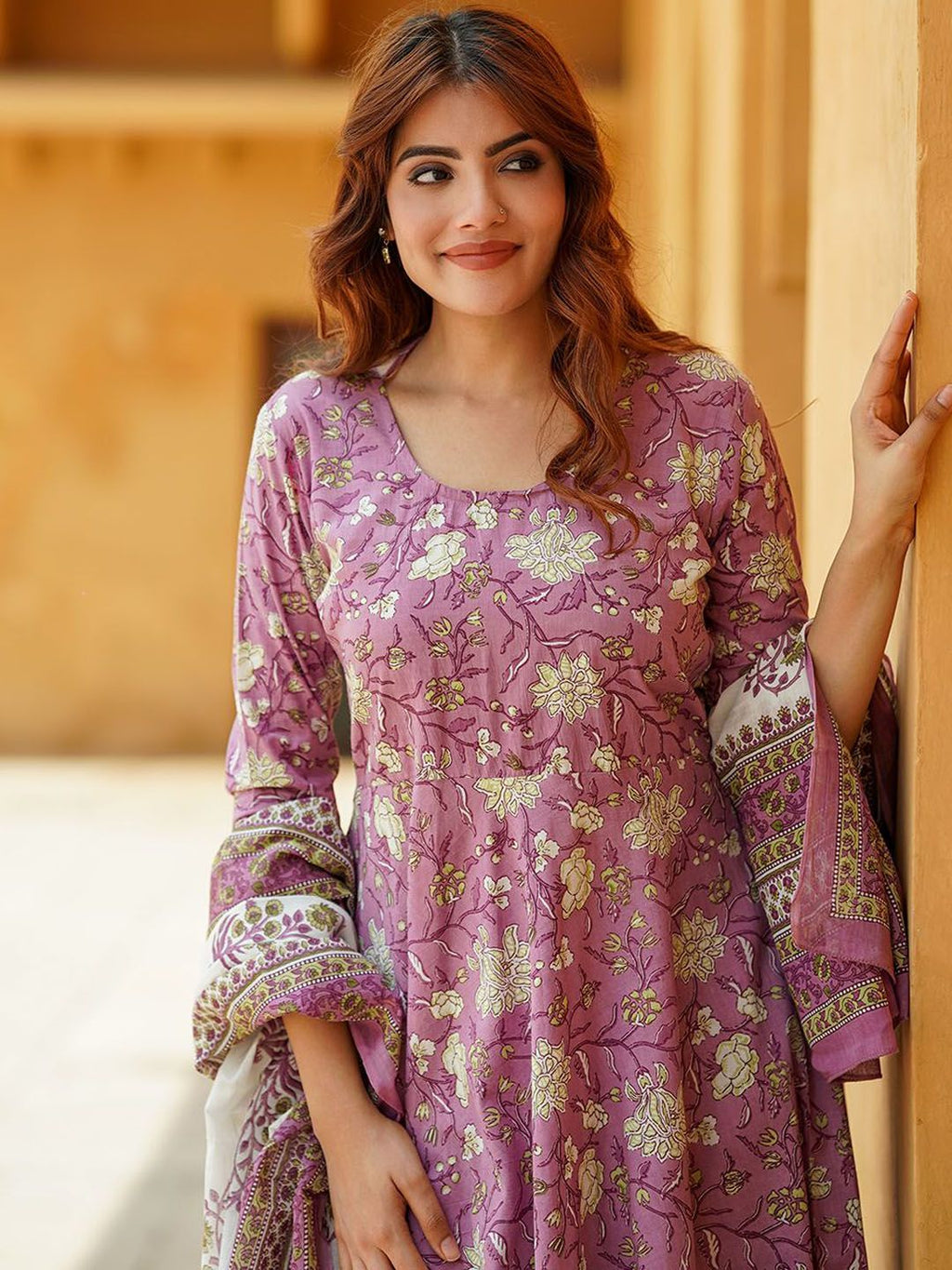 Woman wearing a purple floral embroidered outfit indoors.