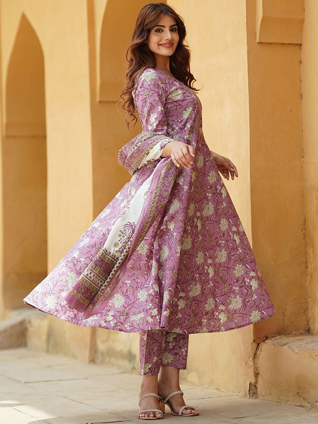 Woman wearing a traditional outfit with floral patterns in an outdoor setting.