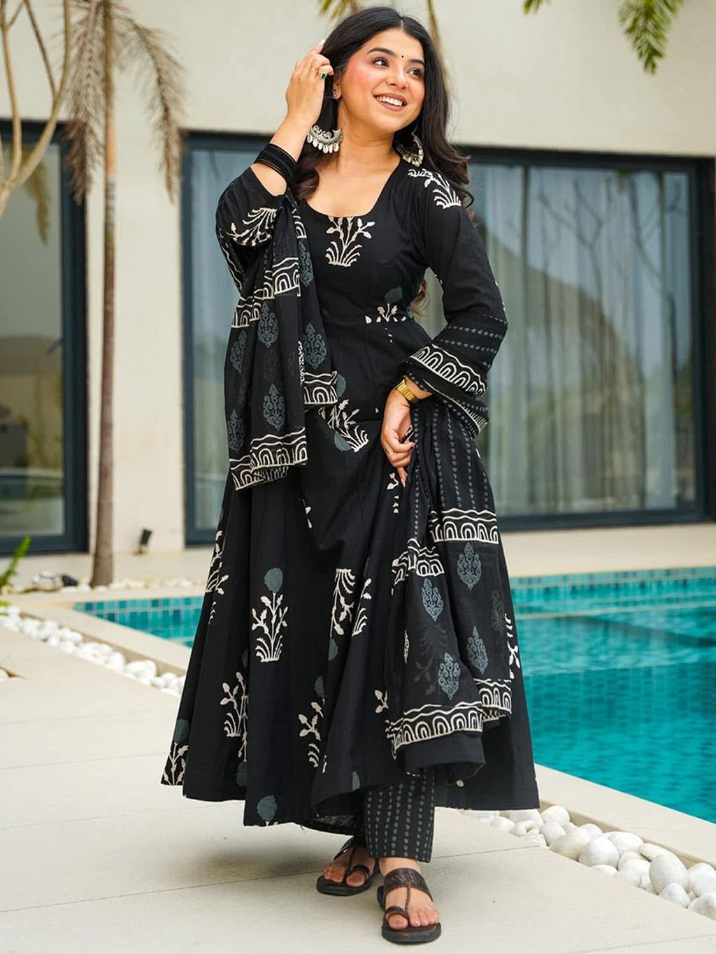 Woman in a black and white patterned outfit standing by a pool.