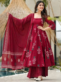 Woman in a red traditional outfit with a matching dupatta, standing outdoors.