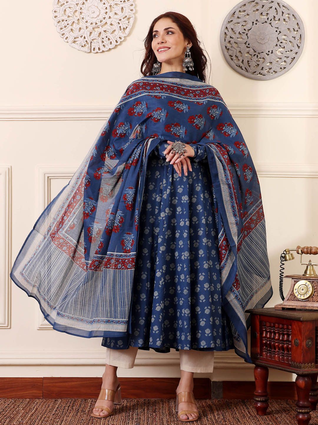 Woman wearing a blue floral dress with a matching shawl in a decorative room.