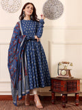 Woman in a blue floral dress with a matching shawl in a room with a vintage telephone and table.