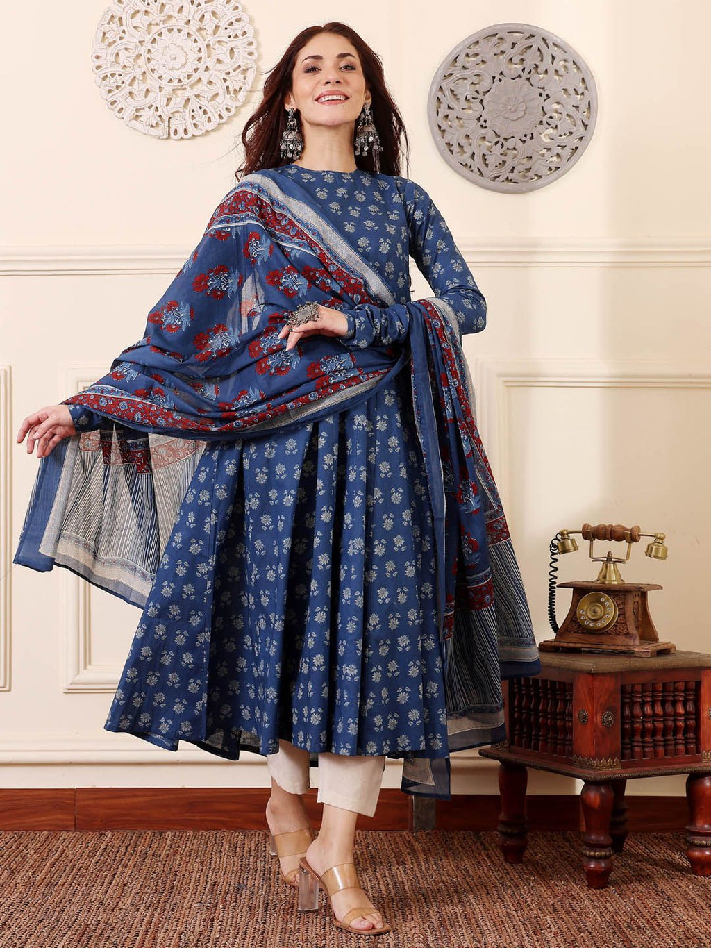 Woman wearing a blue traditional outfit with a matching shawl in a decorated room.