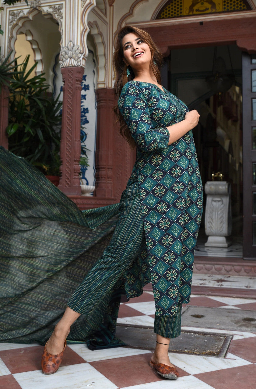 Woman in a green patterned outfit standing in an ornate indoor setting