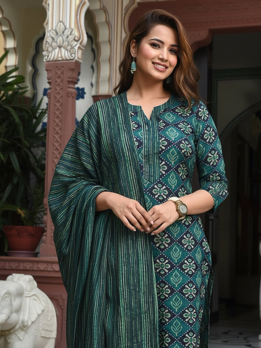 Woman wearing a green patterned outfit standing indoors with decorative elements in the background