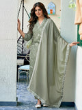Woman in a green traditional outfit standing in an outdoor setting.