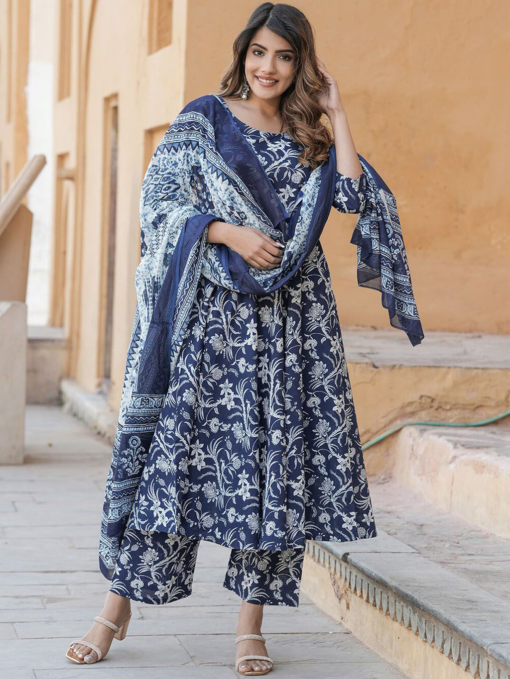 Woman wearing a blue and white patterned outfit with a matching shawl outdoors.