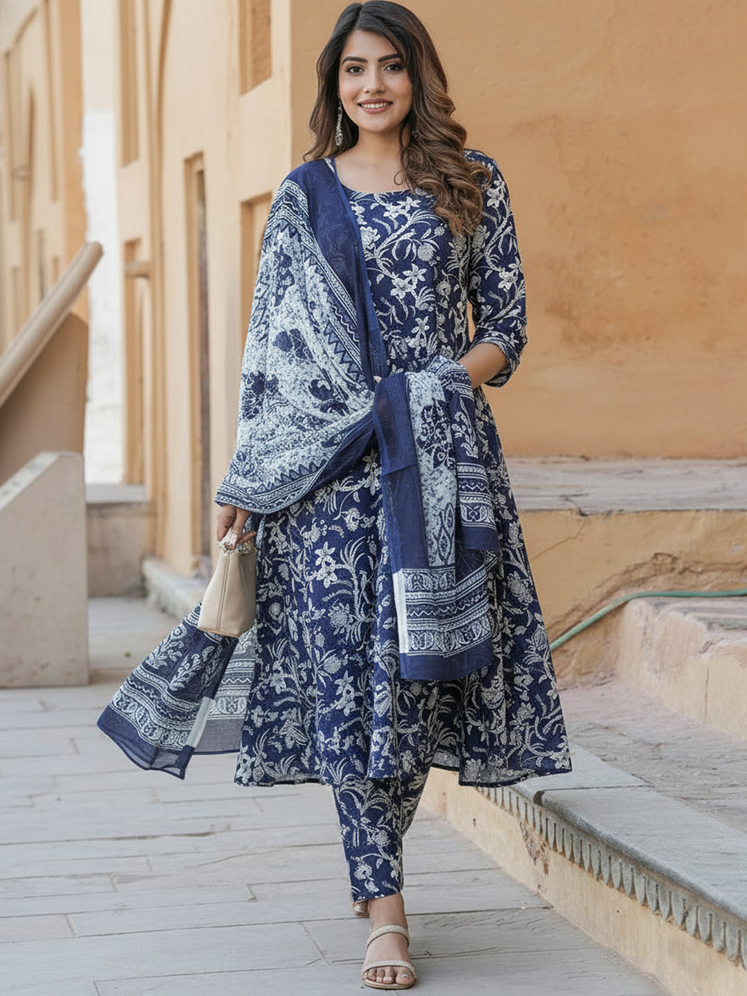 Woman wearing a blue and white patterned outfit standing in front of a beige wall.