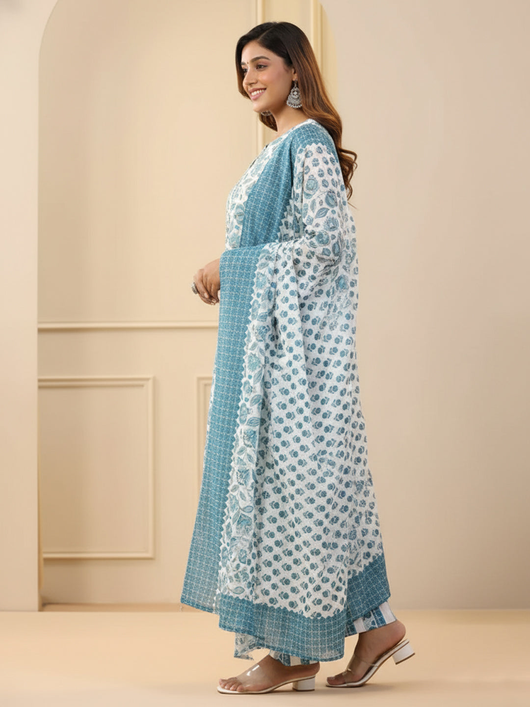 Woman wearing a blue and white patterned dress against a beige wall.