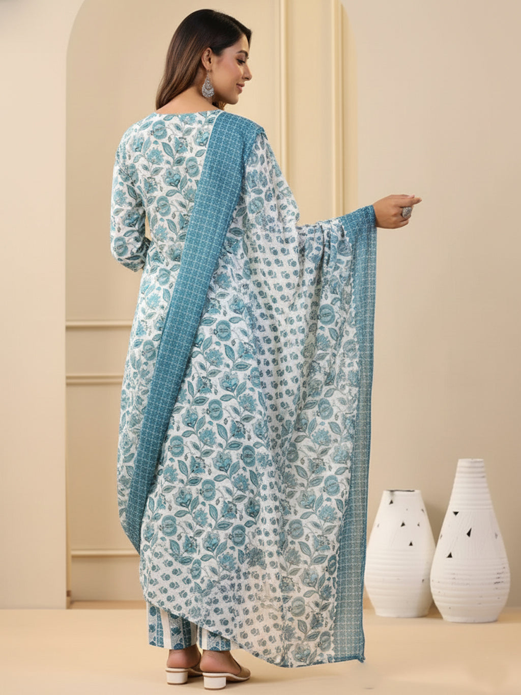 Woman wearing a floral dress with a blue dupatta in a minimalistic setting.