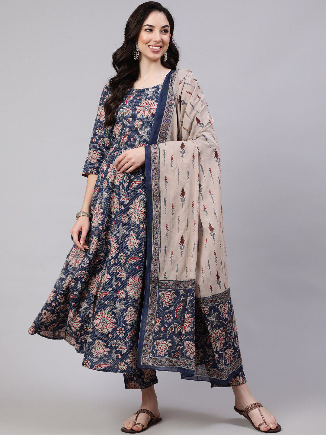 Woman wearing a floral dress with a matching dupatta on a gray background
