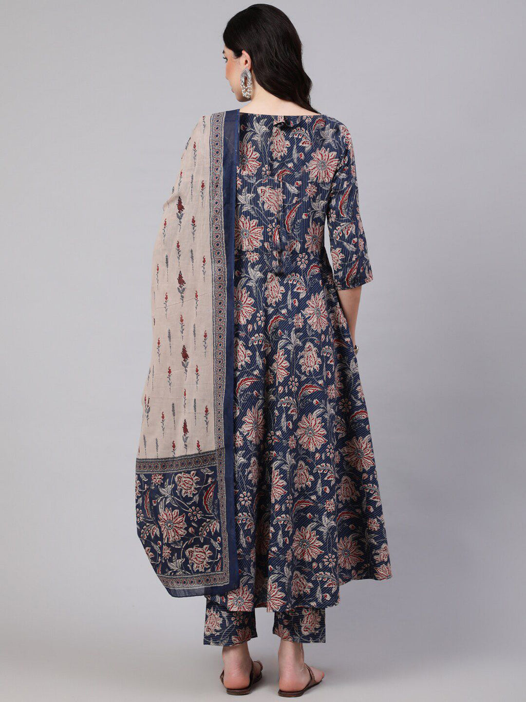 Woman wearing a navy floral print outfit with a matching dupatta on a gray background