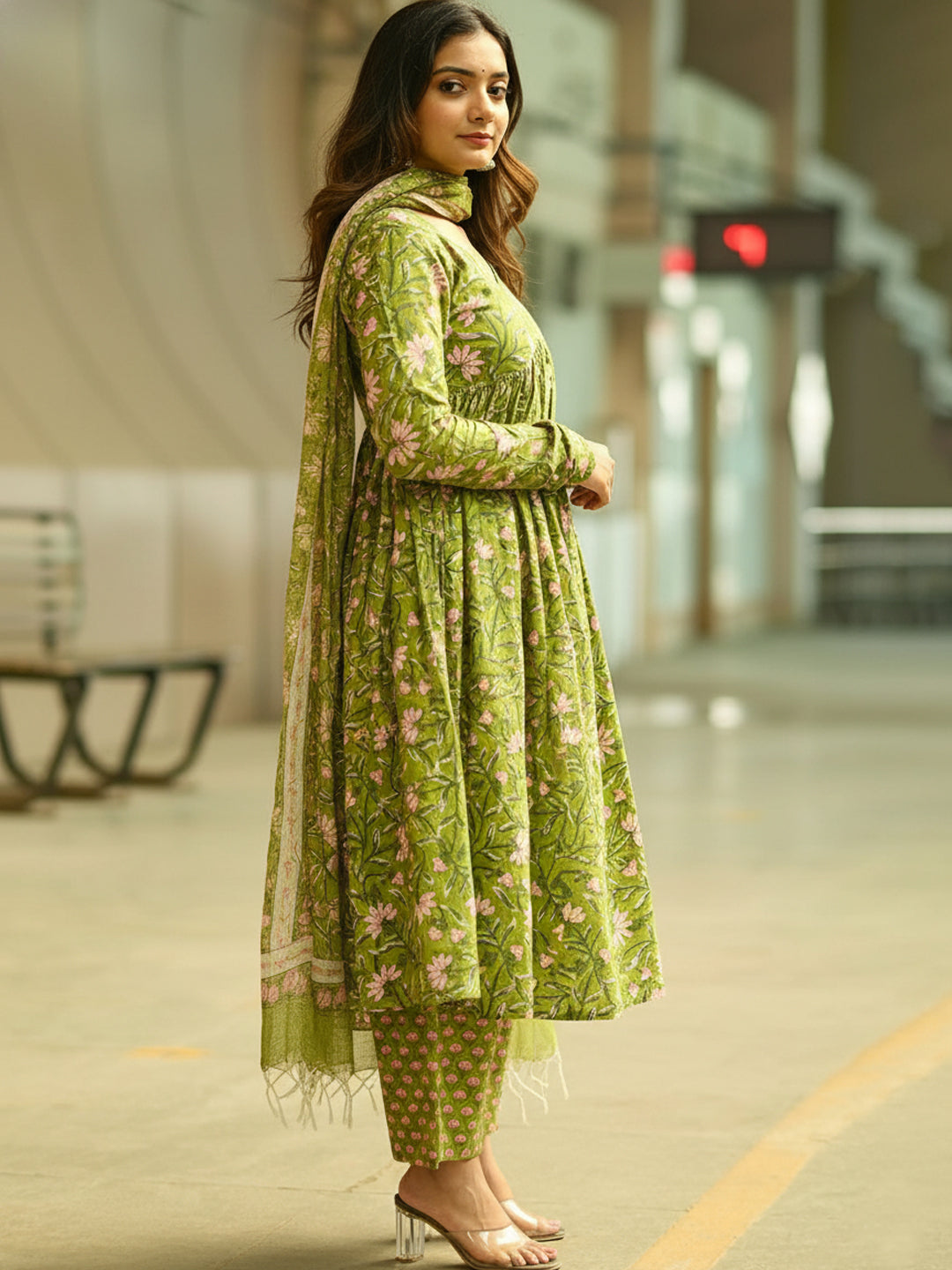 Woman in a green floral outfit standing in an indoor setting