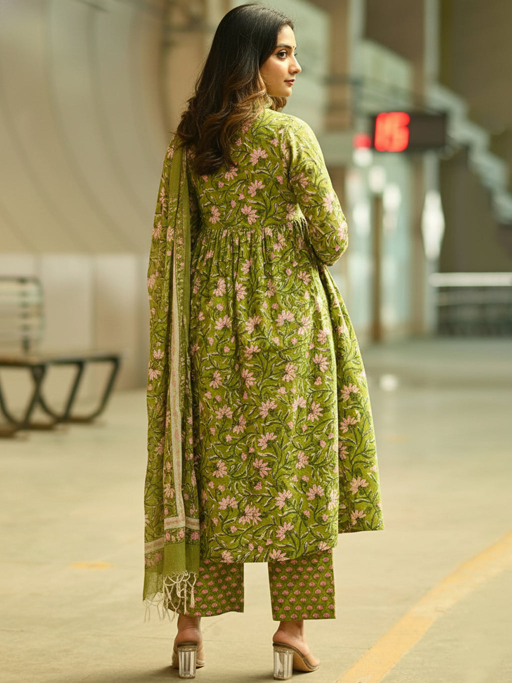Woman in a green floral outfit walking in an urban setting