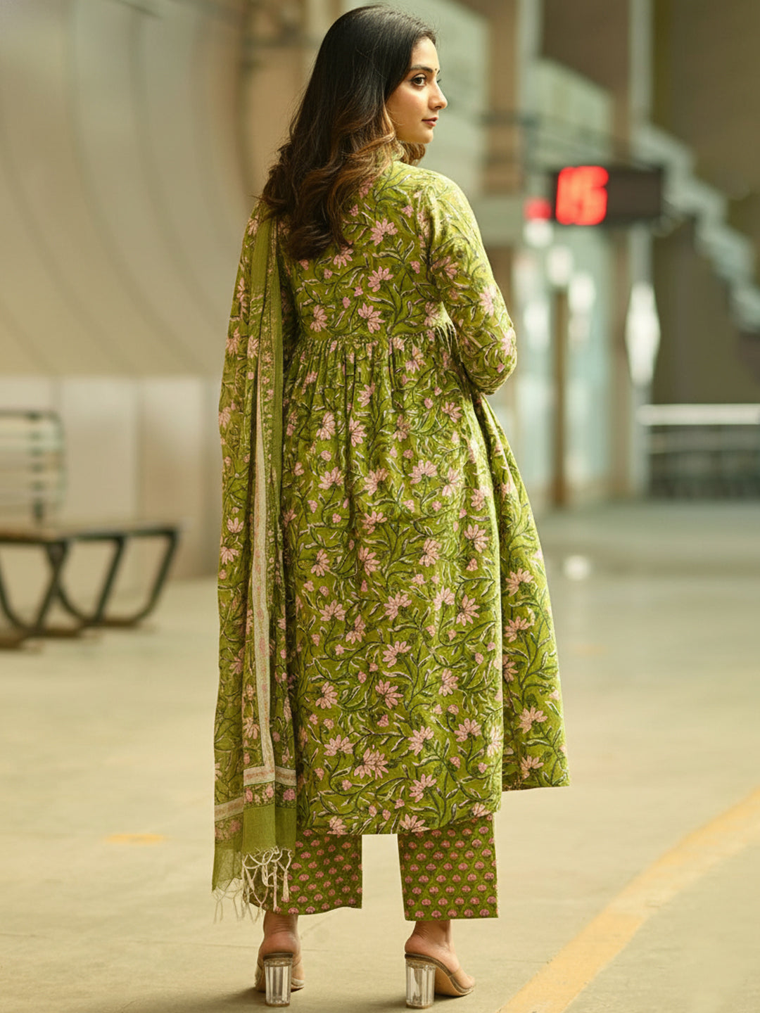 Woman in a green floral outfit walking in an urban setting