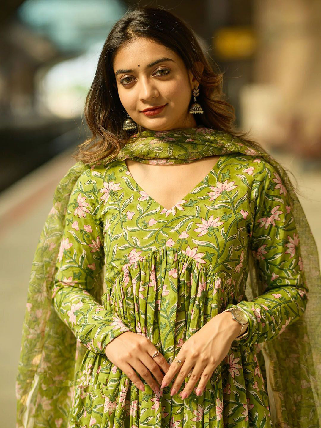 Woman wearing a green floral dress with a matching dupatta in an outdoor setting