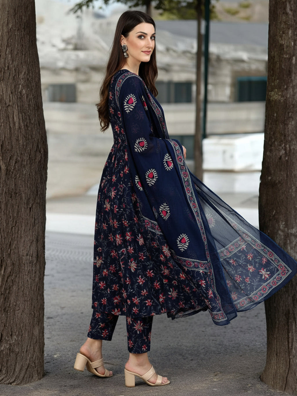 Woman wearing a navy blue traditional outfit with floral patterns in an urban setting.
