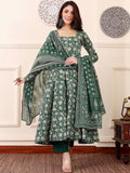 Woman wearing a green traditional outfit with a matching shawl in a decorative room.