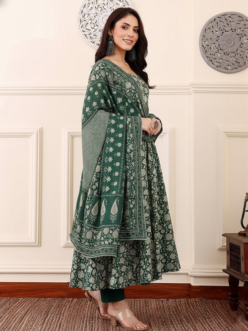 Woman wearing a green patterned dress in an elegant room.