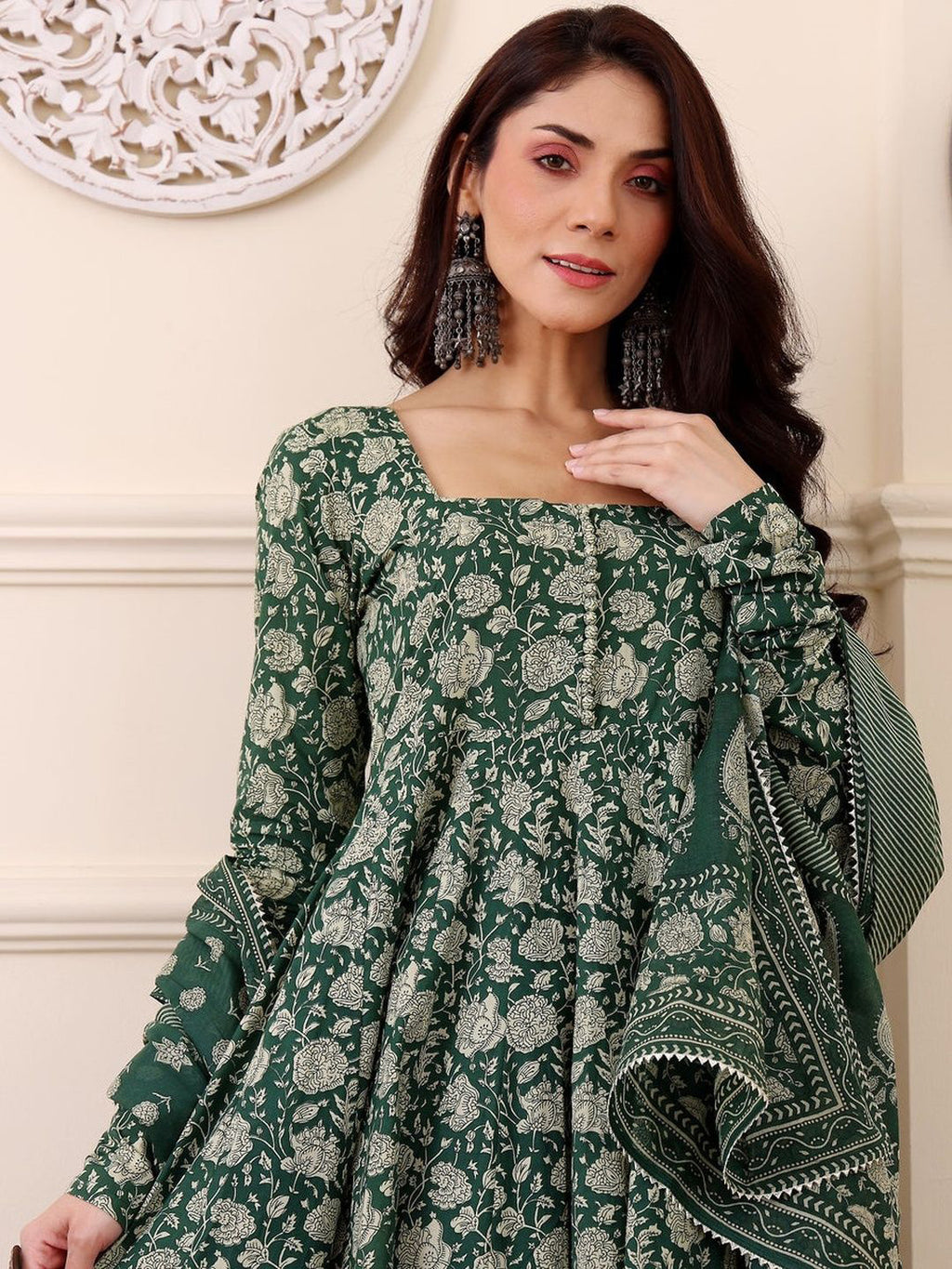 Woman wearing a green floral dress with a matching shawl indoors.
