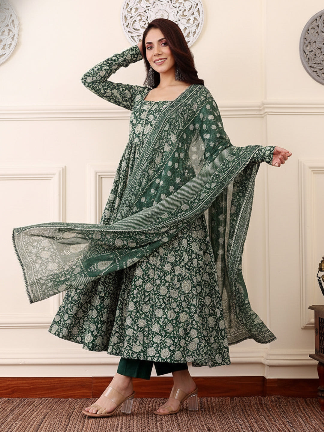 Woman wearing a green floral traditional outfit with a matching dupatta in a room.
